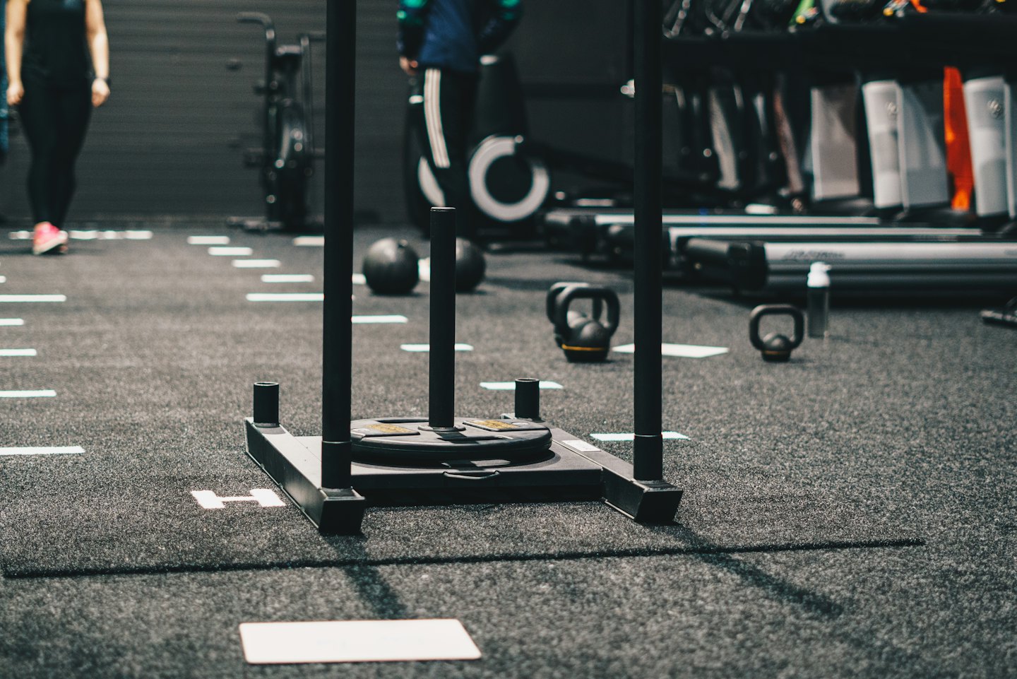 Weight sled on gym floor with exercise equipment.