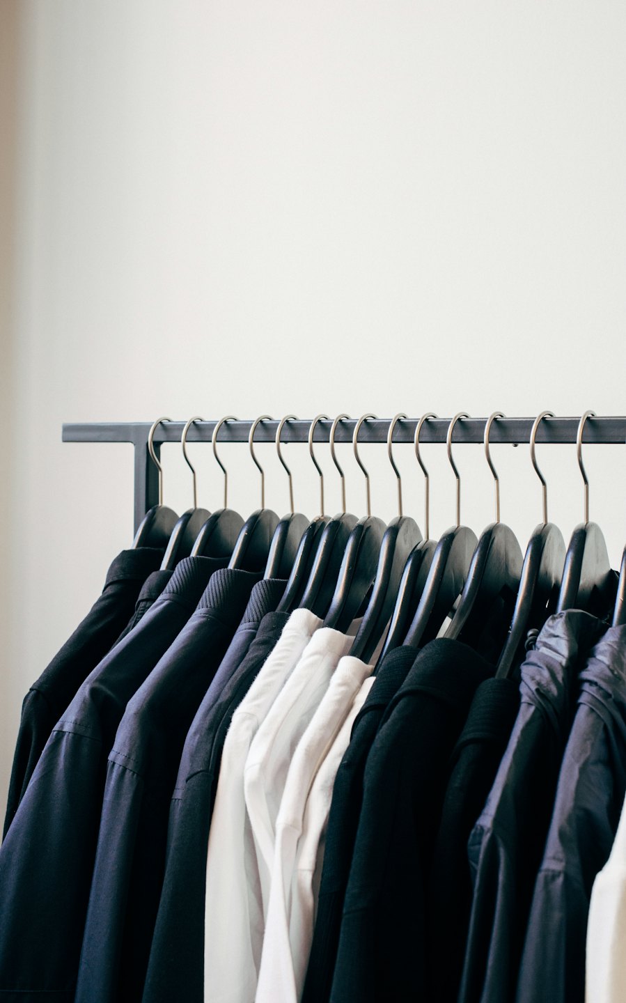 Dark shirts and jackets on a clothing rack.