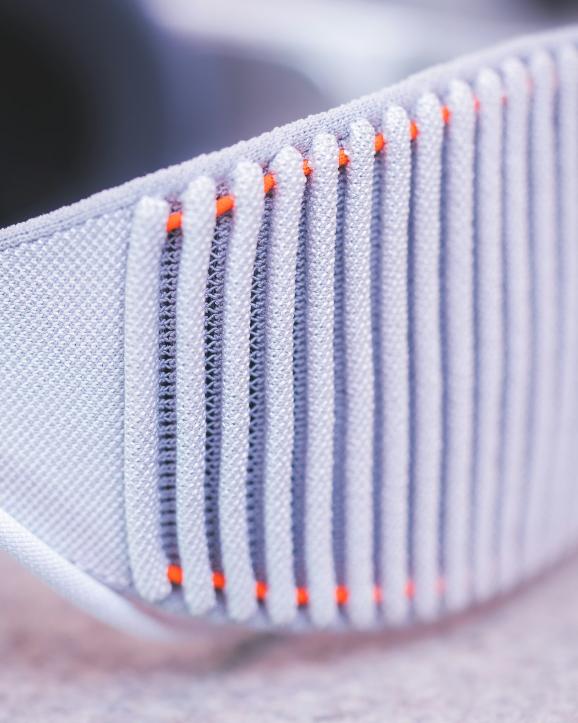 Light grey athletic fabric with ribbed texture and orange stitching.